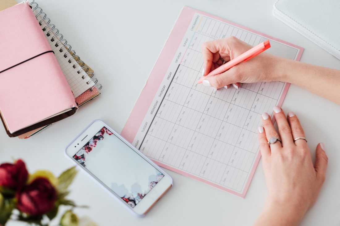 Profissional planejando a semana em agenda física com caneta