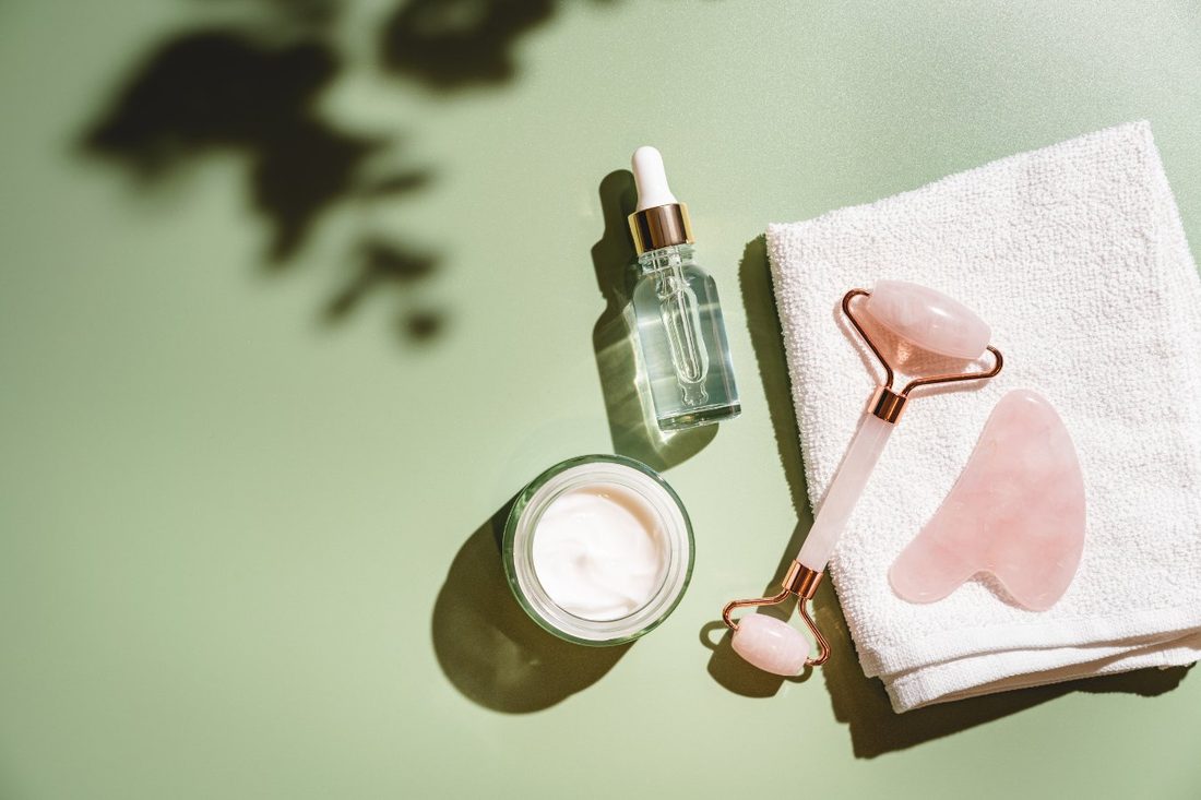 Sérum, creme e rolo de quartzo rosa sobre toalha